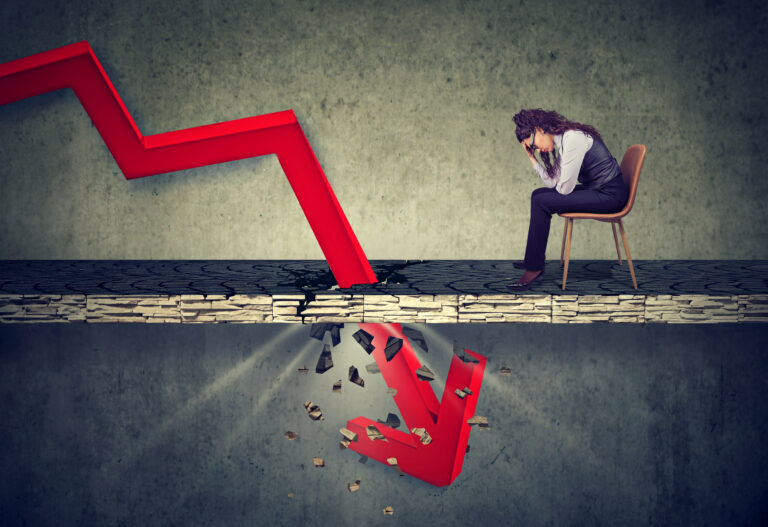 Depressed business woman looking down at the falling red arrow going through a concrete floor