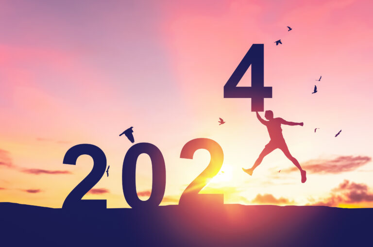 Man jumping on sunset sky with birds flying at top of mountain a